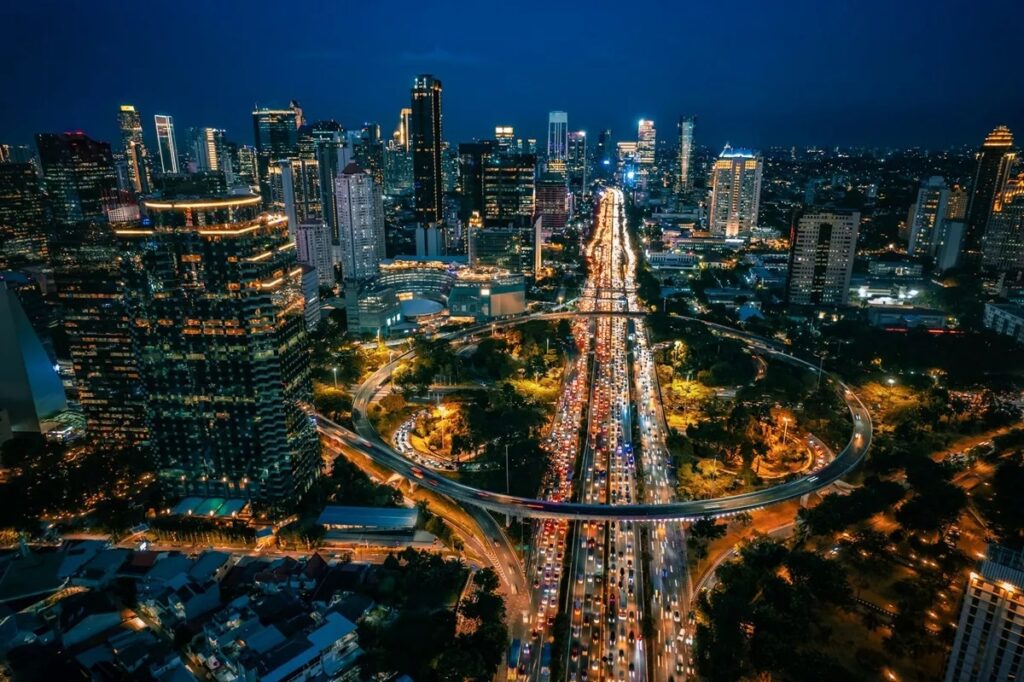 Pemandangan kawasan Bundaran HI Jakarta di malam hari yang terang benderang dengan aktivitas warga yang berjalan kaki dengan nyaman di trotoar. (Sumber Foto: Unsplash@ArifRamdasura)