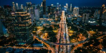 Pemandangan kawasan Bundaran HI Jakarta di malam hari yang terang benderang dengan aktivitas warga yang berjalan kaki dengan nyaman di trotoar. (Sumber Foto: Unsplash@ArifRamdasura)
