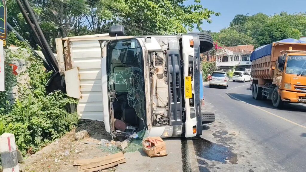 Sebuah truk kontainer pengangkut air mineral terguling dan menghantam sepeda motor serta warung di Jalan Raya Cirebon–Kuningan, Kecamatan Talun, Kabupaten Cirebon. (Foto : Darfan)
